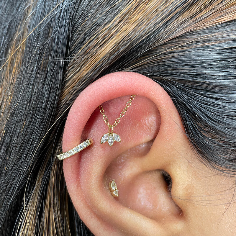 Close up of womans ear wearing a hidden helix chain with triple marquise charm.