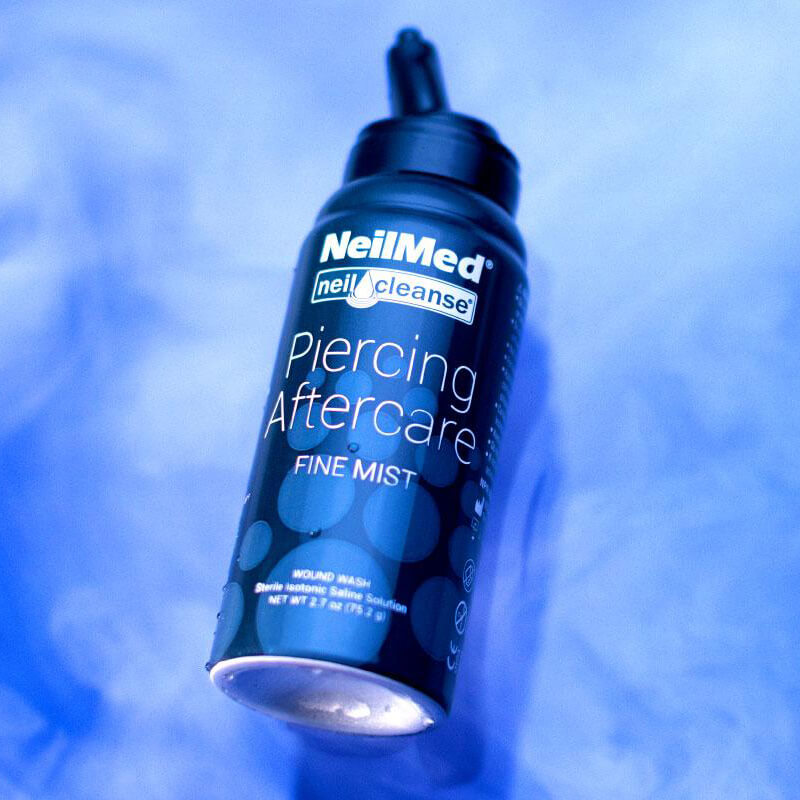 Close-up of a bottle of NeilMed piercing aftercare spray on a blue background
